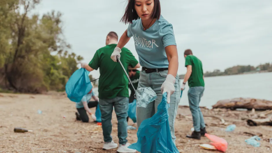 Blick auf eine Gruppe Freiwilliger, die am Flussufer Müll einsammeln